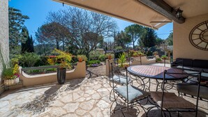 Un patio al aire libre con suelo de piedra, mobiliario de metal y plantas en macetas.