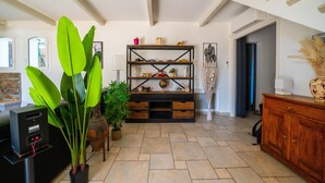 Una sala de estar con un mueble de madera para centro de entretenimiento, una planta grande y un jarrón con flores secas.
