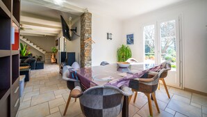 Un comedor moderno con una mesa de vidrio, sillas y un pilar de piedra.