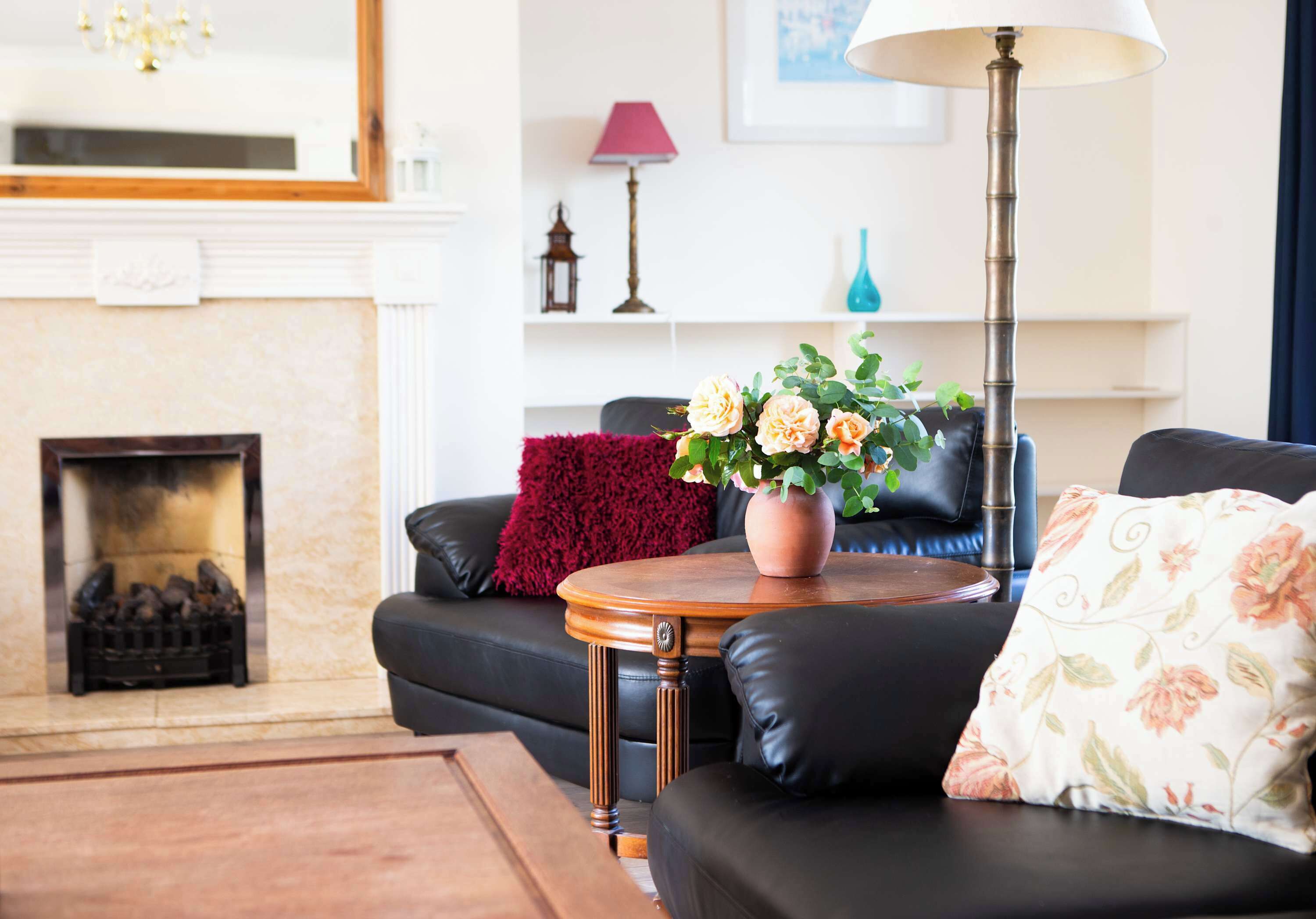 Un salon avec une cheminée, un canapé, une table basse et une lampe.