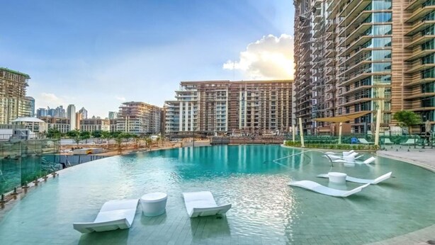 Una piscina con lettini, circondata da edifici alti.