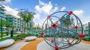 Una struttura sferica con nodi rossi, circondata da un percorso curvo e vegetazione, con edifici moderni sullo sfondo.