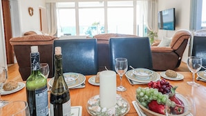 A dining area with a table set for two, featuring a bottle of wine, a candle, and a fruit bowl. - Flat 17 Golden Gates (Poole)