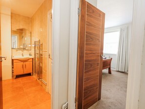 A hotel room with a bathroom, a wooden wardrobe, and a view of the outside. - Flat 17 Golden Gates (Poole)