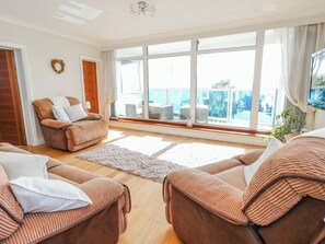 A spacious living room with large windows, a sofa, a chair, and a rug. - Flat 17 Golden Gates (Poole)