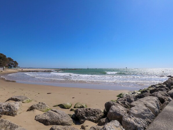 A beach with a rocky shoreline, clear blue sky, and calm sea. - Flat 17 Golden Gates (Poole)