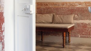 Ein Zimmer mit Schachbrettfußboden, einer Couch mit Kissen, einer weißen Tür und einer Ziegelwand.