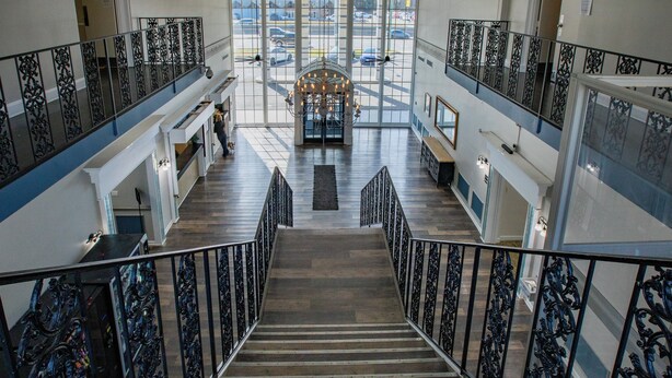 A grand staircase with ornate railings, leading to a spacious lobby with large windows and a chandelier. - Modern Mins To "Atrium & Novant" Uptown Char Airport (Charlotte)