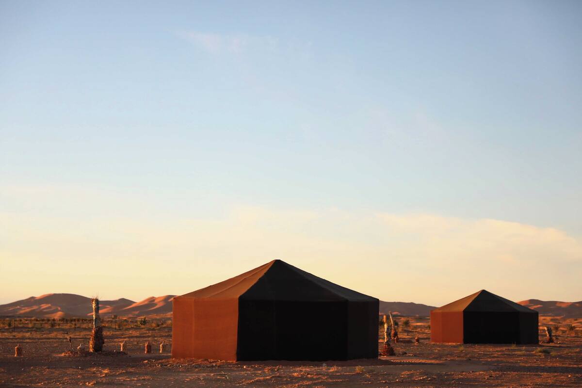 A desert landscape with two large, dark tents.