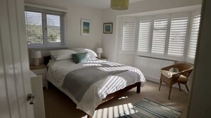 A bedroom with a bed, a chair, a window with blinds, and a radiator. - Spacious Home in the Cotswolds, Parking & Garden (Westmancote)
