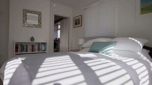 Una camera da letto con un letto, una libreria, uno specchio e una finestra con persiane.