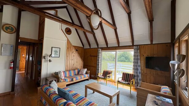 Un interior de madera con un sofá, sillas, una mesa y un televisor.