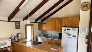Cocina con armarios de madera, una isla central, microondas, refrigerador y un lavamanos.