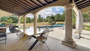 An outdoor patio with a table and chairs, columns, and a view of a swimming pool. - Petite house “La Grande Rivière” with pool, Wi-Fi, and air conditioning (Sèvremoine)