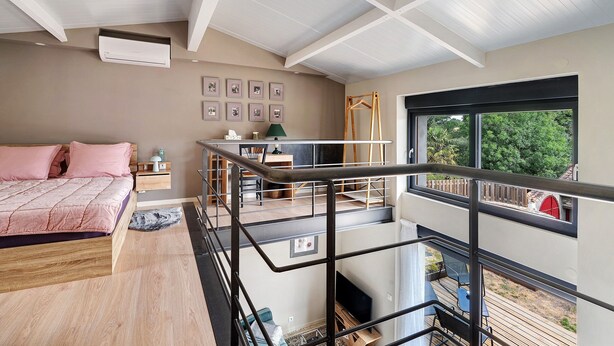 A bedroom with a bed, a desk, a chair, a window, and a balcony with a view of greenery. - Petite house “La Grande Rivière” with pool, Wi-Fi, and air conditioning (Sèvremoine)