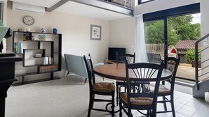 A dining area with a round table and chairs, a bookshelf, and a staircase leading to an upper level. - Petite house “La Grande Rivière” with pool, Wi-Fi, and air conditioning (Sèvremoine)