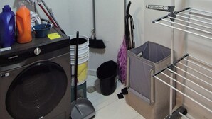 A laundry room with a washing machine, mops, brooms, and a drying rack. - Centrally located apartment in Guadalajara in one of the best neighborhoods in the city. (Guadalajara)