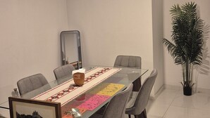 A dining area with a glass table, grey upholstered chairs, a framed picture, and a potted plant. - Centrally located apartment in Guadalajara in one of the best neighborhoods in the city. (Guadalajara)