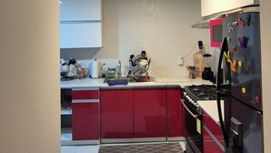 A kitchen with red cabinets, a black refrigerator, and a tiled floor. - Centrally located apartment in Guadalajara in one of the best neighborhoods in the city. (Guadalajara)