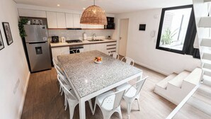Una cucina moderna con mobili bianchi, un piano di lavoro in granito e un'area pranzo con sedie bianche.