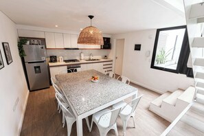 A modern kitchen with white cabinets, a granite countertop, a stainless steel refrigerator, and a dining area with white chairs. - MOT Rentals + 4 Bd 3 Ba Terrace, Pool and BBQ Palermo (Buenos Aires)
