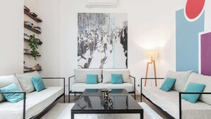 Un soggiorno moderno con un divano, un tavolino da caffè e un grande quadro astratto appeso al muro.