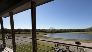 Uma área externa coberta com vista para um lago e mesas de piquenique.