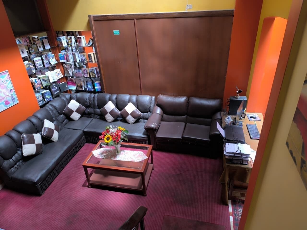 Una habitación con un sofá modular, una mesa de centro con un arreglo floral y una estantería llena de libros.