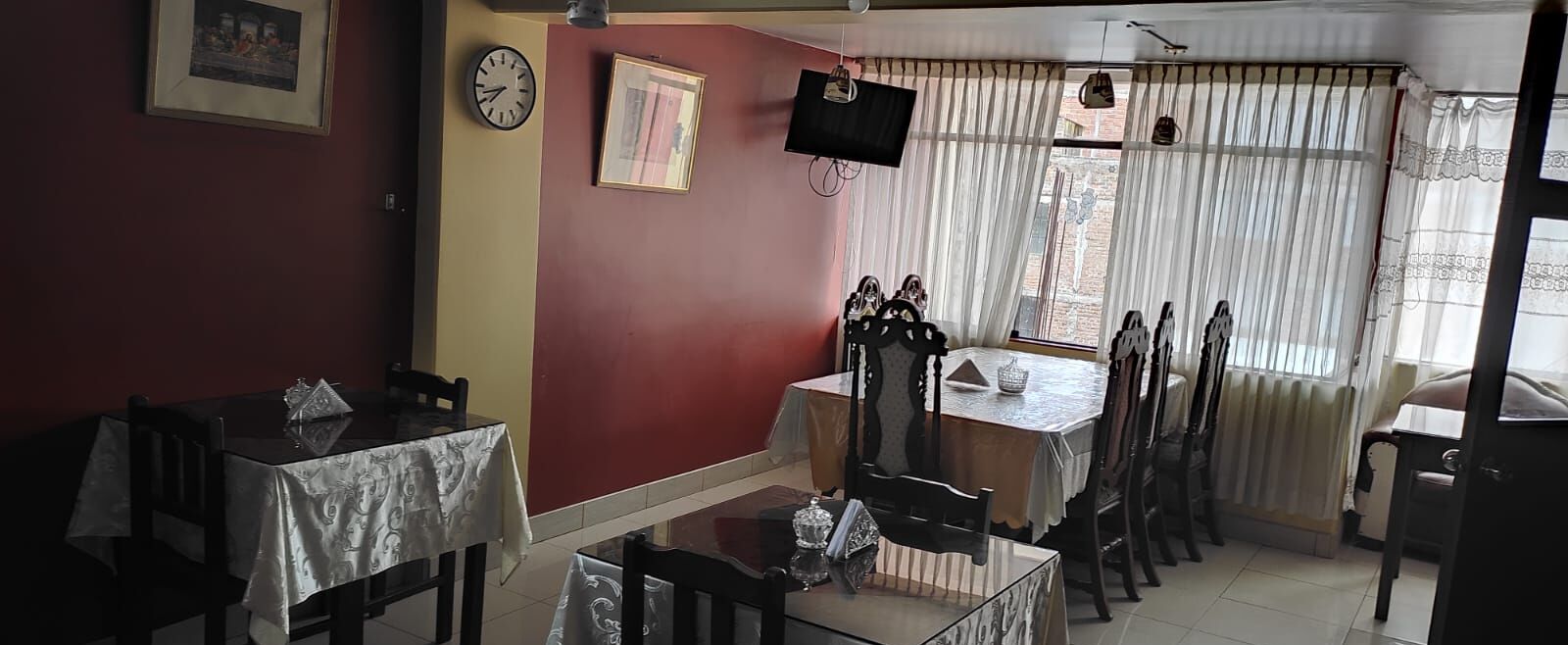 Ein Essbereich mit Tisch, Stühlen, einer Uhr und einem Fernseher an der Wand.