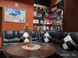 Un área de descanso moderna con un sofá de cuero, una mesa de centro de madera y una estantería llena de libros y revistas.