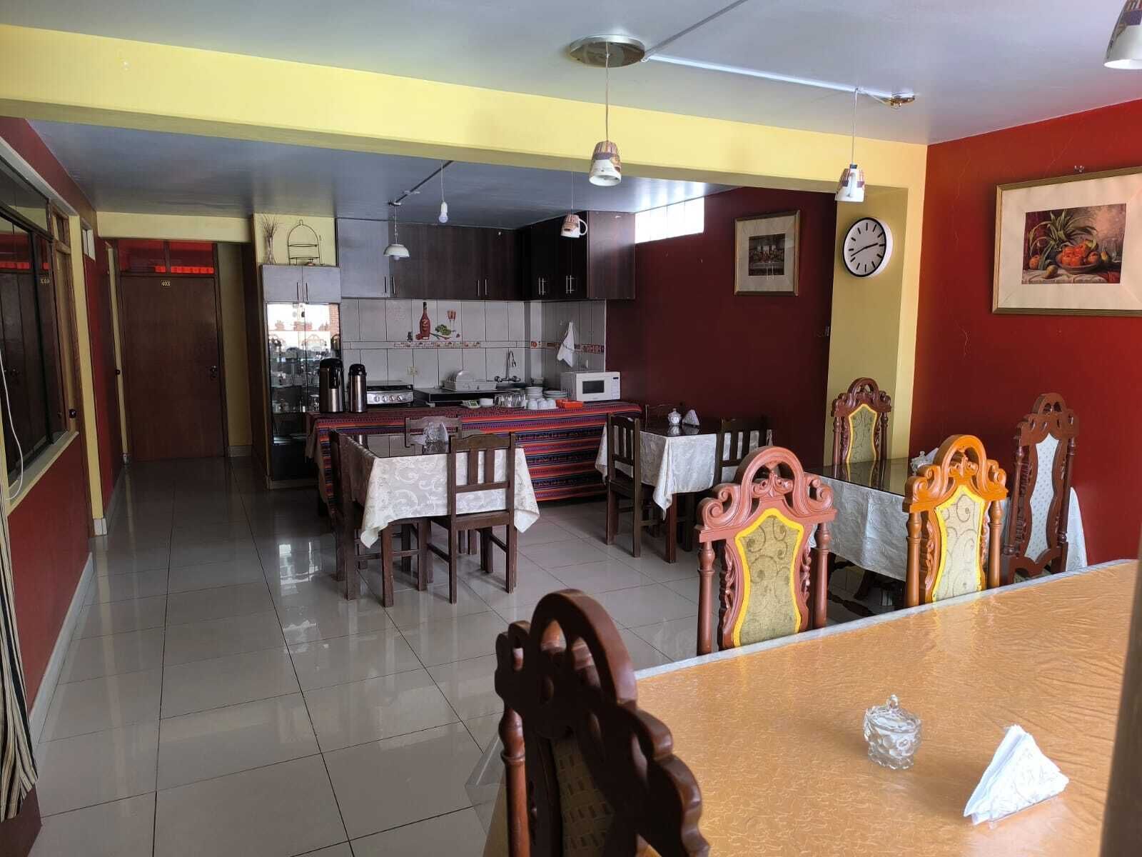 A dining area with a wooden table, chairs, and a kitchen in the background.