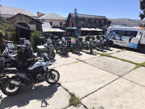 A row of motorcycles parked on a concrete surface with a bus in the background.