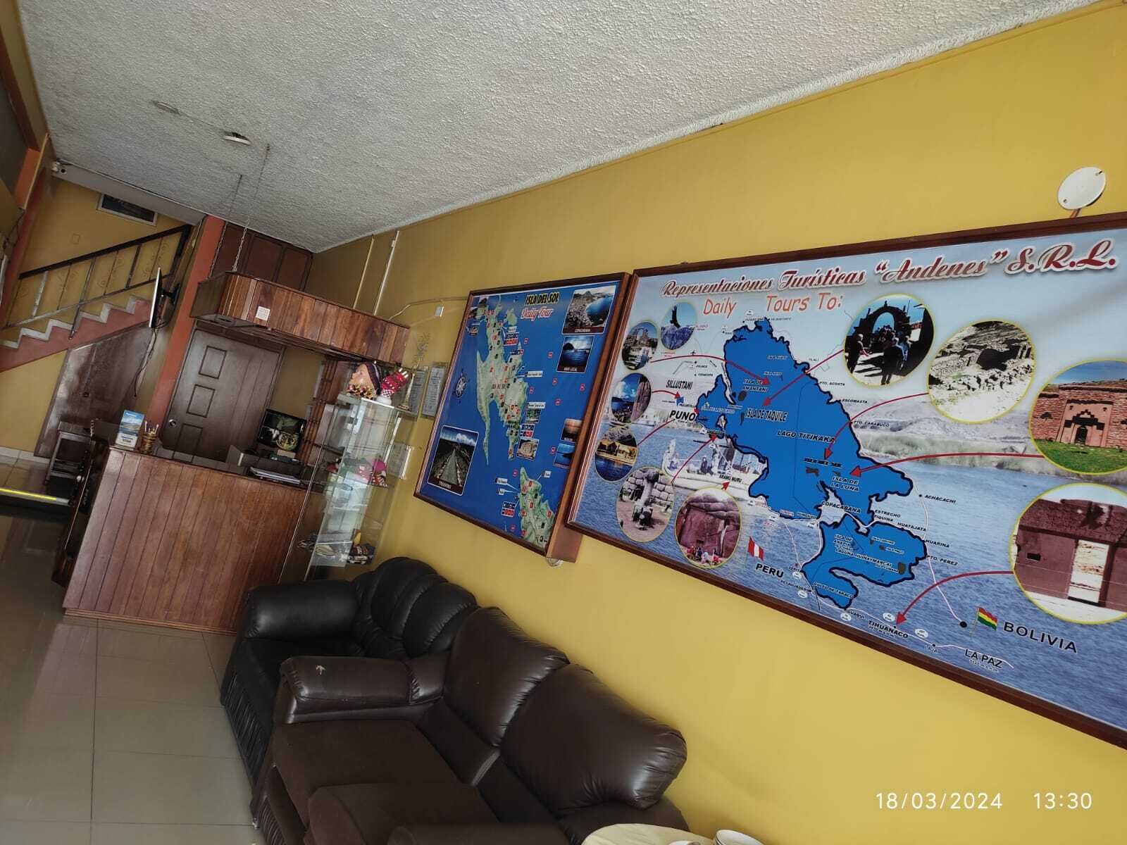 Un vestíbulo de hotel con un mapa grande, una escalera, un armario de madera y un sofá de cuero.