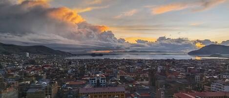 Paisagem urbana com edifícios, um corpo de água e uma montanha ao fundo.