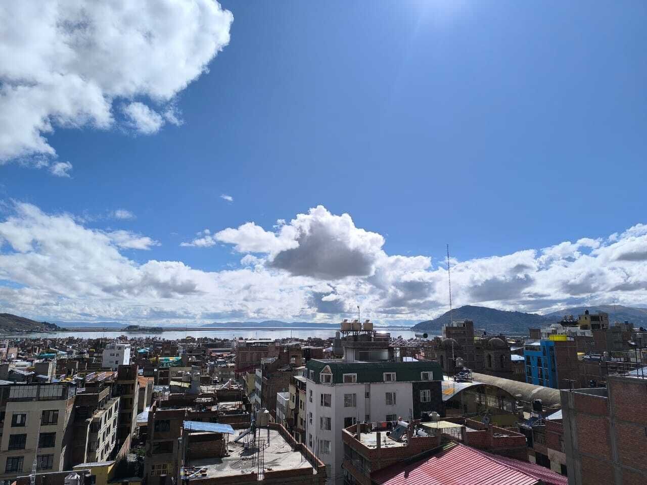 A cityscape with buildings, a clear sky, and distant mountains.