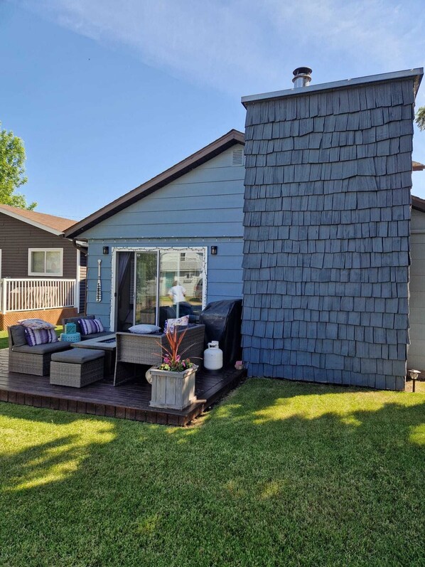 A house with a deck, outdoor furniture, and a chimney.