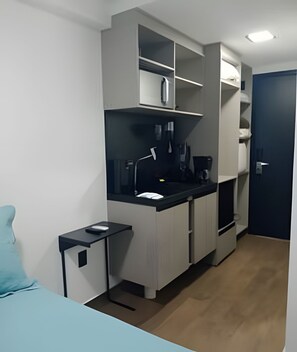 A compact kitchenette with a countertop, cabinets, and a small table. - Move Oásis Tambaú (Joao Pessoa)