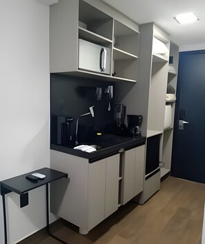 A compact kitchenette with a coffee maker, a small table, and a door. - Move Oásis Tambaú (Joao Pessoa)