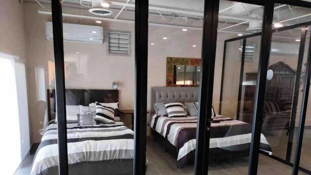 A hotel room with three beds, a large mirror, and a sliding glass door. - Suite Buenavista 301 y 302 (La Paz)