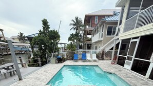 A swimming pool with two separate sections, surrounded by a tiled deck and lounge chairs. - Private Canal Retreat - Heated Pool & Spa (Fort Myers Beach)