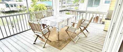 A covered outdoor area with a table and chairs, a ceiling fan, and a view of the surrounding area.