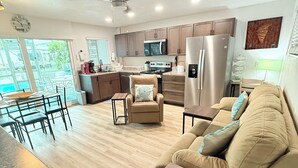 A modern kitchen with a microwave, refrigerator, and dining area with a table and chairs. - Private Canal Retreat - Heated Pool & Spa (Fort Myers Beach)