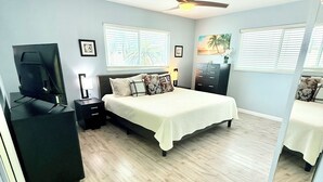 A bedroom with a bed, a television on a stand, a ceiling fan, and a window with blinds. - Private Canal Retreat - Heated Pool & Spa (Fort Myers Beach)