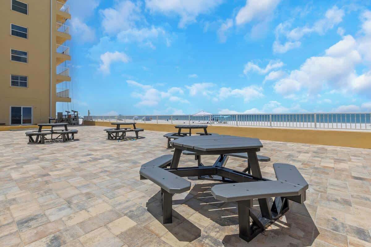 Ein Patio im Freien mit Picknicktischen und Blick auf den Strand.