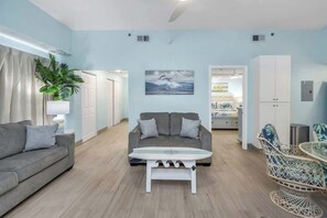 A living room with a sofa, a coffee table, a chair, and a plant. - Beachfront Paradise! Crawl 2 beach~Beachfront Pool (Indian Rocks Beach)