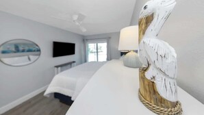 Ein Hotelzimmer mit einem Bett, einem Flachbildfernseher, einer Lampe und einer dekorativen Holzskulptur.