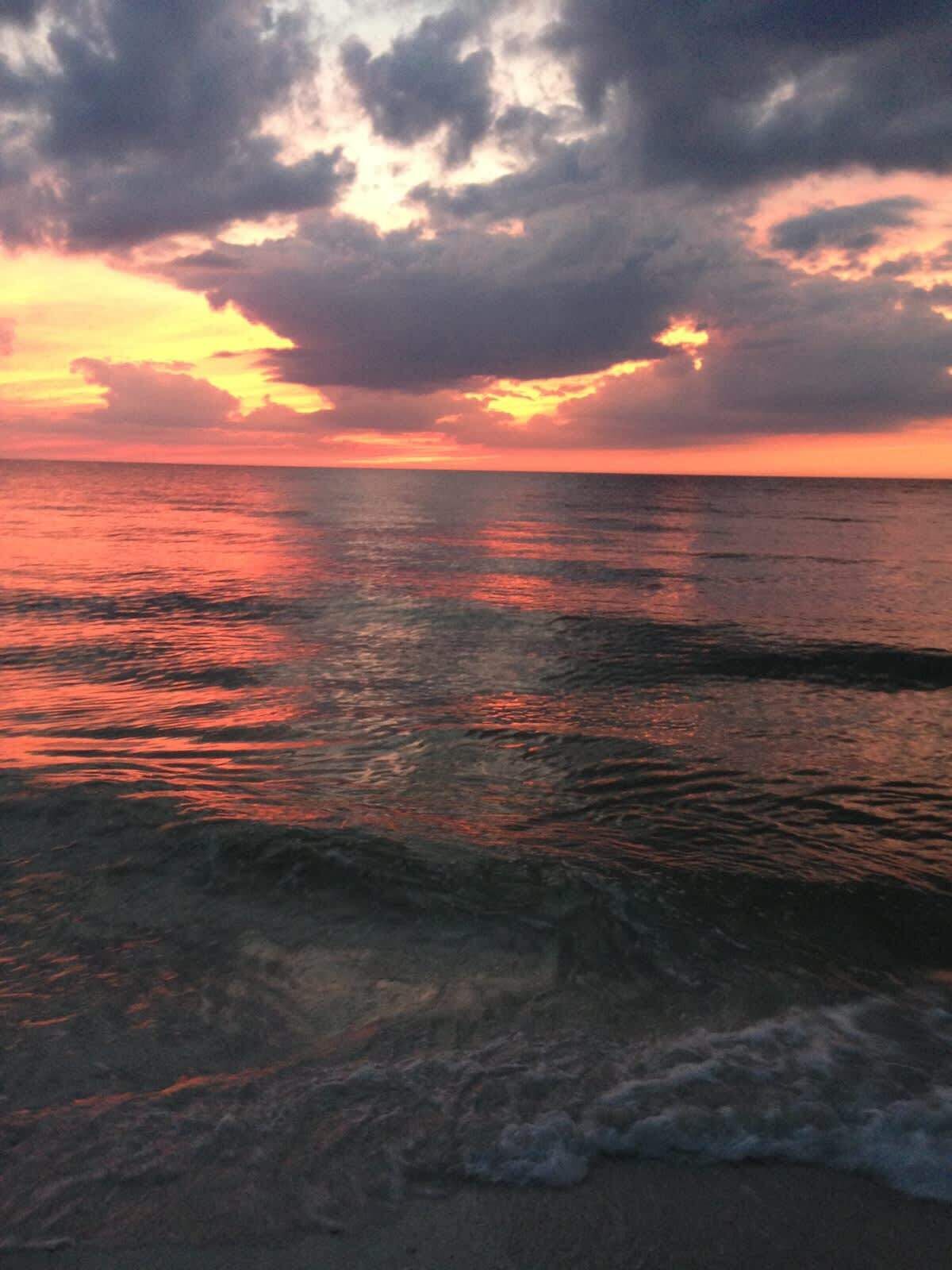 A sunset over a body of water with waves.