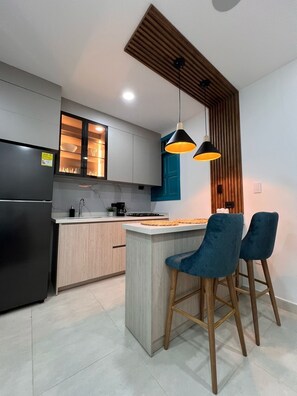Une cuisine moderne dotée d’un îlot central, de tabourets de bar et de luminaires suspendus.
