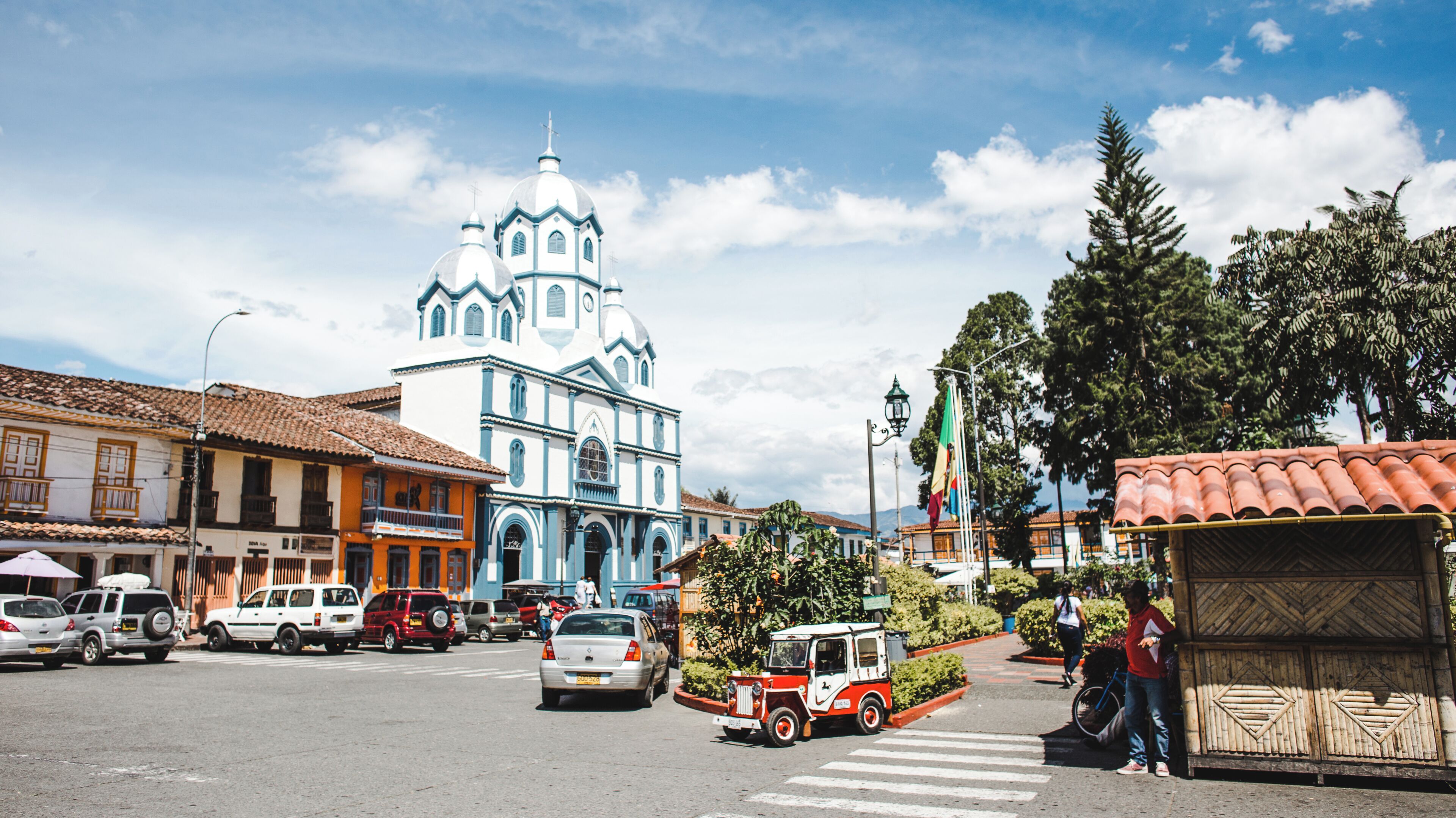 Una calle con una iglesia destacada, vehículos y peatones.