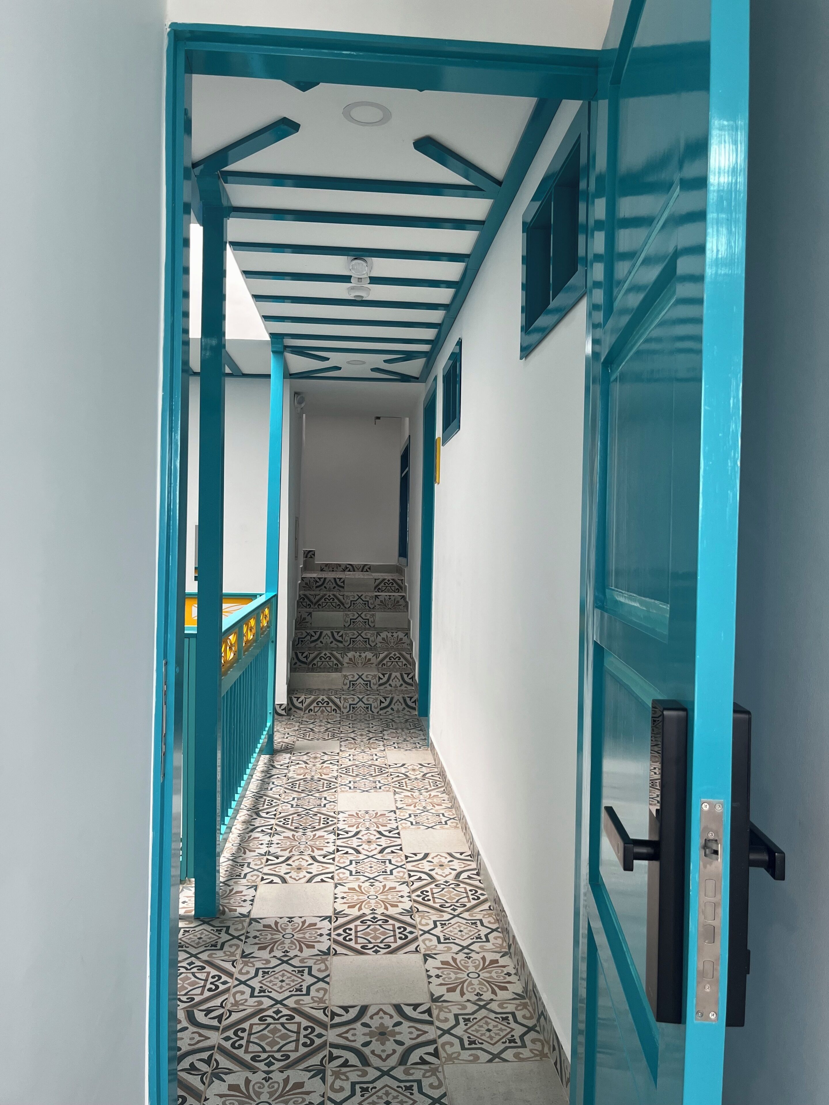 A hallway with patterned floor tiles, a blue door frame, and a staircase leading to an upper level.